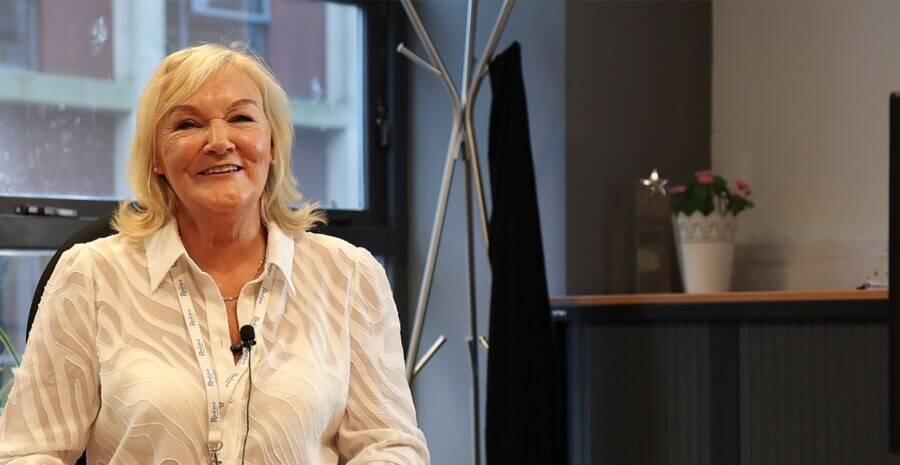 A woman wearing a Radius lanyard sitting in her office, smiling at the camera